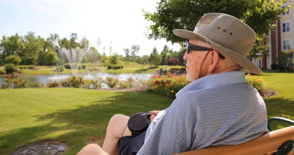 Elderly man sitting on a bench overlooking a lake
